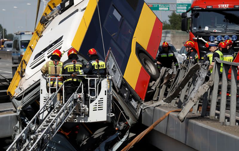 Emergency personnel work at the site of a crash after a city bus fell off a motorway bridge in Warsaw