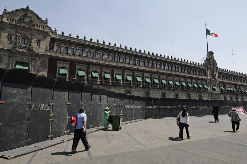 People walk past a perimeter fence set up in front of the National Palace in preparation for the upcoming International Women's Day demonstration, in Mexico City, Friday, March 5, 2021. Marked on March 8th, the day has been sponsored by the United Nations since 1975, to celebrate women’s achievements and aims to further their rights. (AP Photo/Eduardo Verdugo)