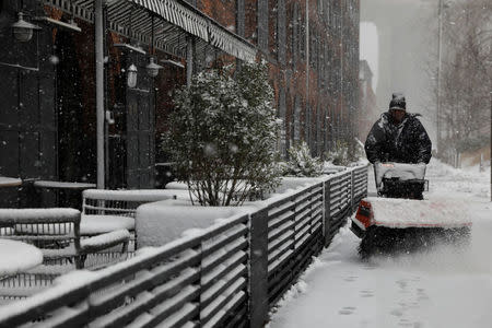 A man uses a snowblower to clear snow, during a nor'easter, near the Brooklyn Bridge Park in Brooklyn, New York, U.S., March 21, 2018. REUTERS/Shannon Stapleton