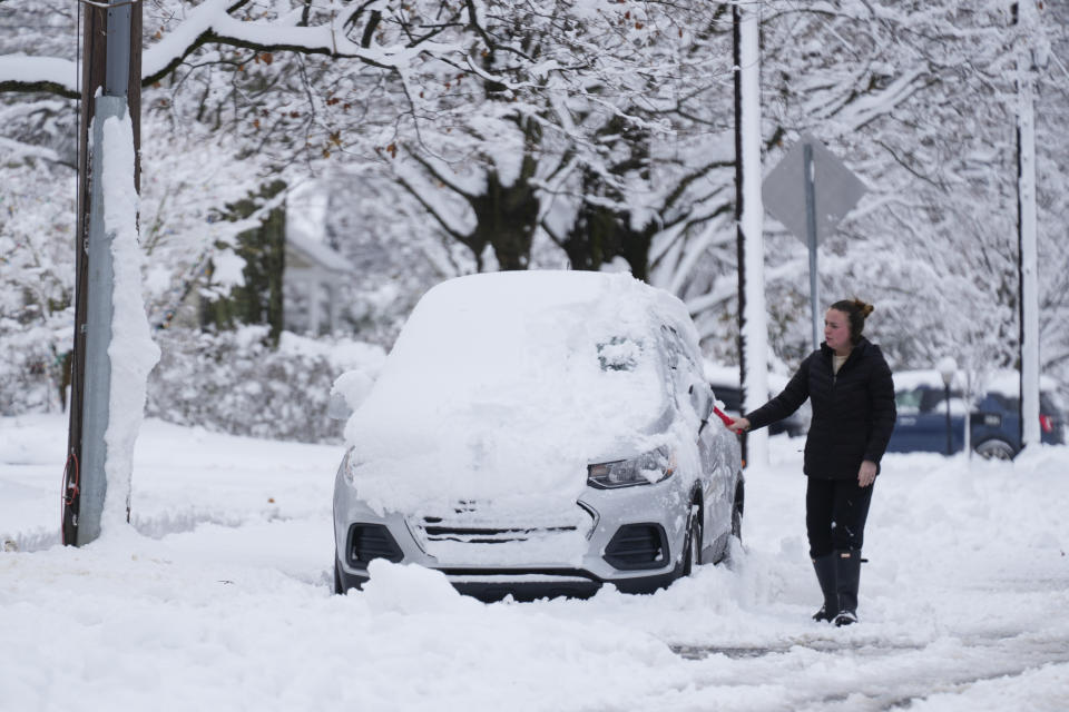 A person clears snow from a car during a winter storm in Doylestown, Pa., Tuesday, Feb. 13, 2024. (AP Photo/Matt Rourke)