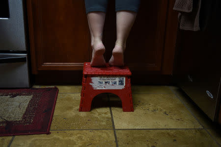 Lauren Hoffmann, 29, a college program manager, stands on a stool to reach a cabinet in her kitchen in San Antonio, Texas, U.S., February 12, 2019. REUTERS/Callaghan O'Hare