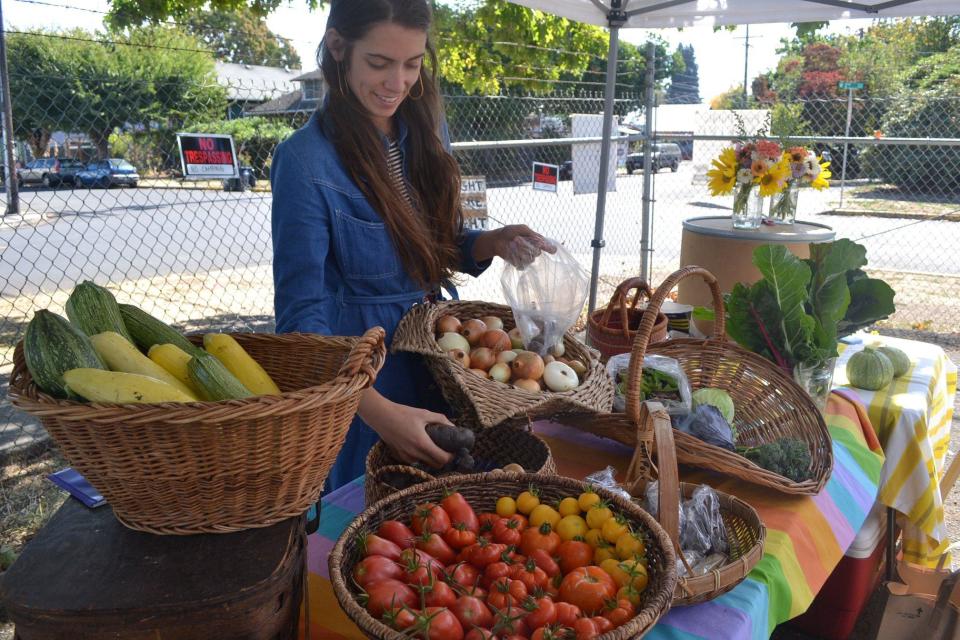 A produce vendor arranges her offerings for sale at a previous Whiteaker Community Market.
