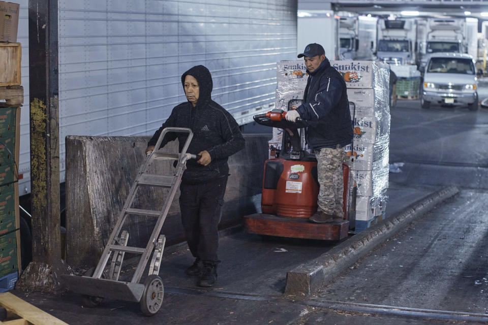 A client, right, transports boxes of oranges as he arrives to shop at S. Katzman Produce inside the Hunts Point Produce Market on Tuesday, Nov. 22, 2022, in the Bronx borough of New York. Hunts Point's wholesalers distribute 2.5 billion pounds of produce a year, with about 30 million pounds having moved on Tuesday alone. The produce ends up at places like Whole Foods, high-end grocers and specialty markets, as well smaller mom-and-pop outlets. Thanksgiving is especially busy time of year because the quintessentially American feast is universally celebrated across the United States. (AP Photo/Andres Kudacki)