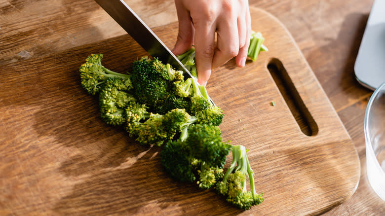 Hand chopping broccoli on board