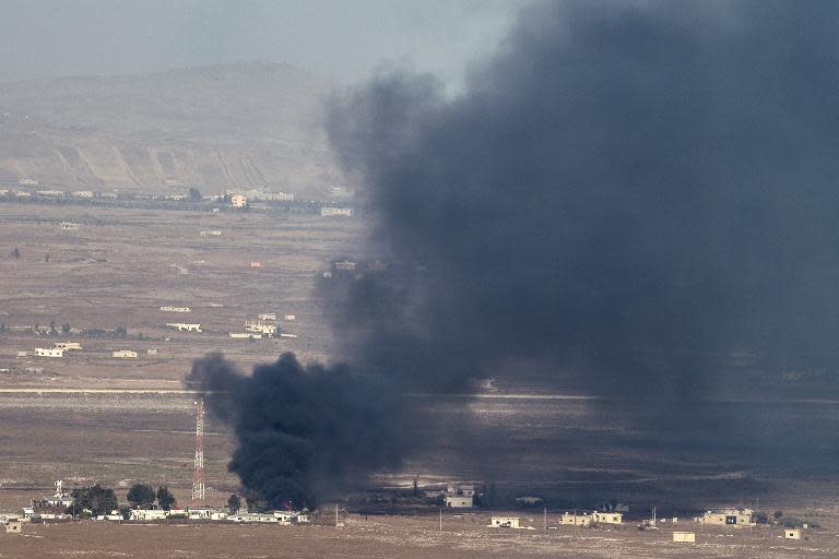 Smoke rise from the Syrian village of Quneitra, seen from the Israeli-occupied Golan Heights, from fighting between forces loyal to President Assad and rebels over the control of the Quneitra border crossing, August 27, 2014