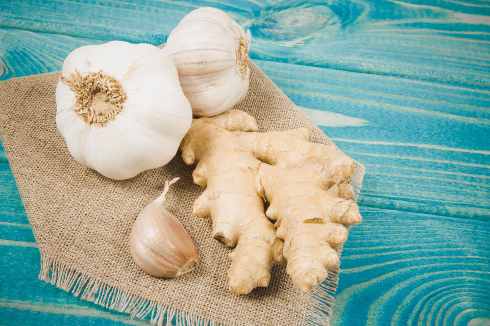 Close up on garlic bulbs with ginger on blue wooden table. Natural remedies for colds.