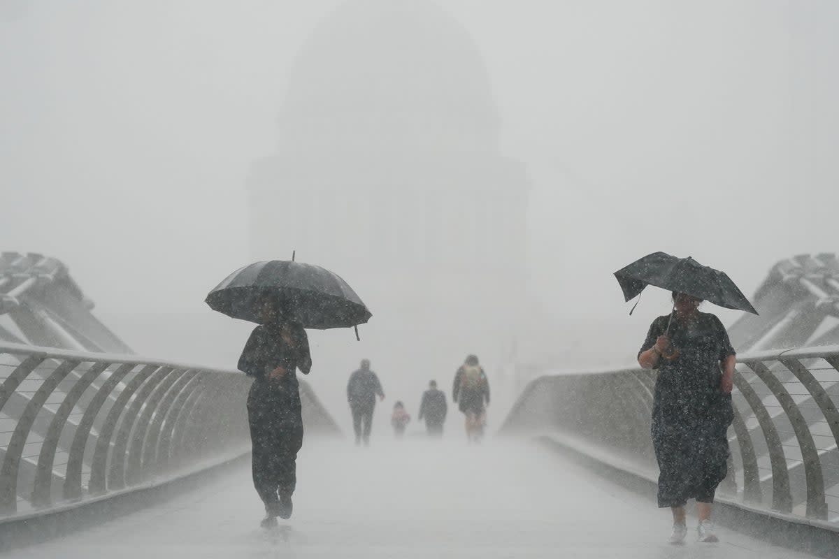 People with umbrellas walking in the rain on Millennium Bridge, London. After weeks of sweltering weather, which has caused drought and left land parched, the Met Office’s yellow thunderstorm warning forecasts torrential rain and thunderstorms that could hit parts England and Wales (Victoria Jones/PA) (PA Wire)