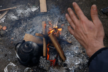 A Kurdish migrant from Iran warms his hands by a fire at a camp in Calais, France, January 11, 2019. Picture taken January 11, 2019. REUTERS/Pascal Rossignol