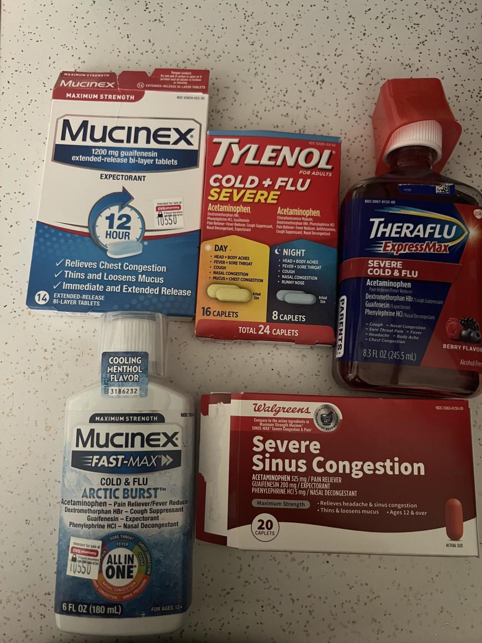 Various cold and flu medications including Mucinex, Tylenol, Theraflu, and Walgreens Severe Sinus Congestion displayed on a countertop