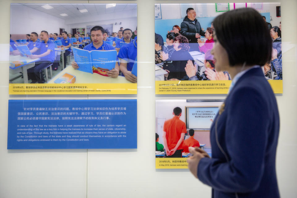 A tour guide stands near a display showing images of people at locations described as vocational training centers in southern Xinjiang at the Exhibition of the Fight Against Terrorism and Extremism in Urumqi in western China's Xinjiang Uyghur Autonomous Region on April 21, 2021. Human rights groups and Western nations led by the United States, Britain and Germany accused China of massive crimes against the Uyghur minority and demanded unimpeded access for U.N. experts at a virtual meeting on Wednesday, May 12, 2021 denounced by China as "politically motivated" and based on "lies." (AP Photo/Mark Schiefelbein)