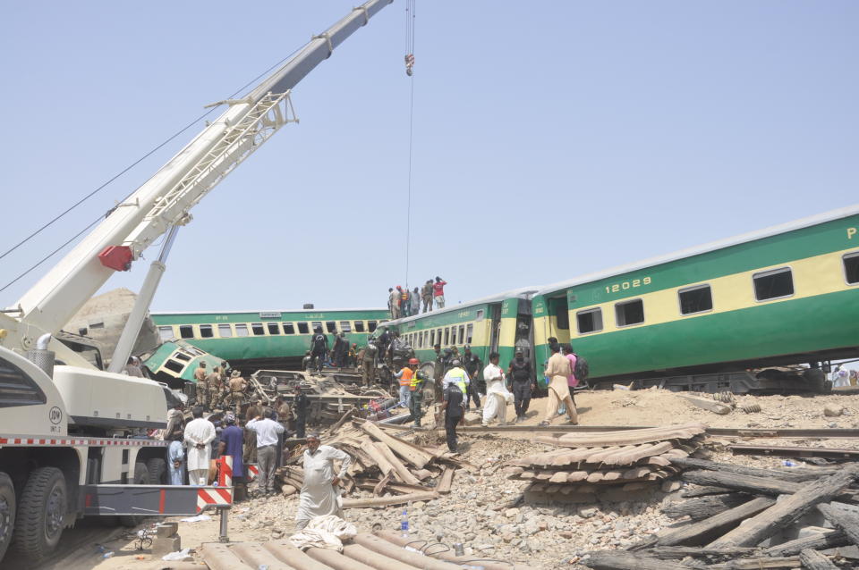 Pakistani officials and volunteers work at a train crash site in Rahim Yar Khan, Pakistan, Thursday, July 11, 2019. A passenger train rammed into a freight train in southern Pakistan on Thursday, killing many people and injuring others, an official said. (AP Photo/Waleed Saddique)