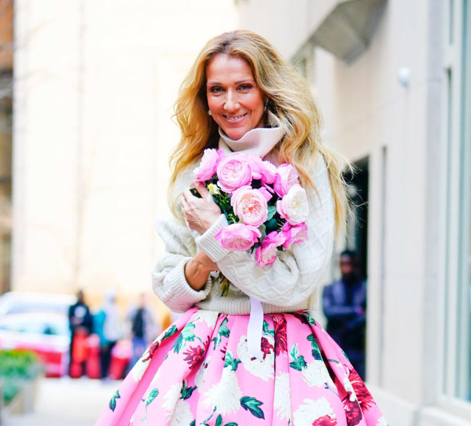 Celine Dion is seen as she departs her hotel wearing a turtleneck sweater and a floral-printed skirt as she holds a bouquet of flowers