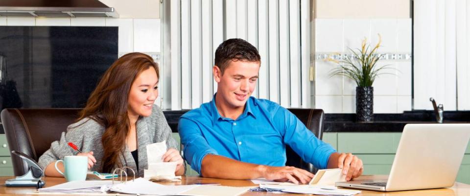 Young couple at the kitchen table, going over their expenses, loans, financial situation and mortgage statements