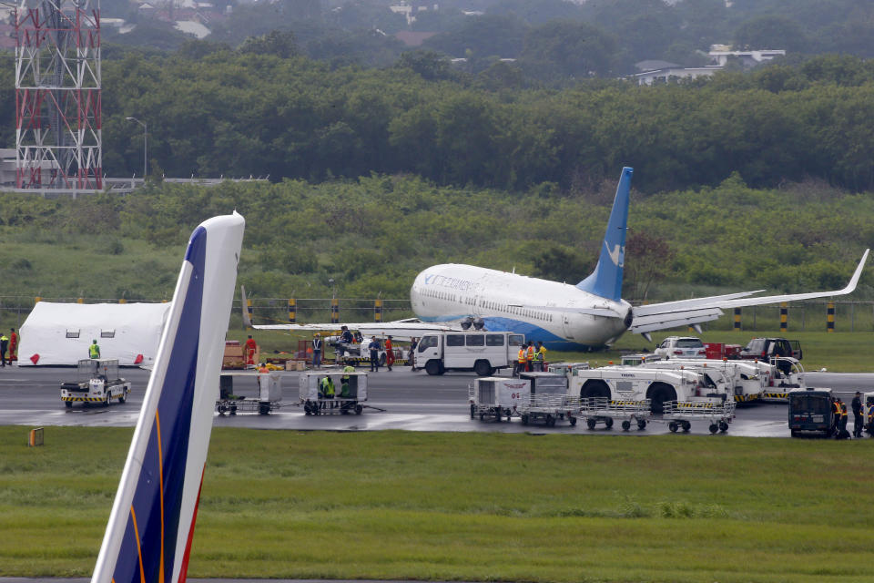 A Boeing passenger plane from China, a Xiamen Air, sits on the grassy portion of the runway of the Ninoy Aquino International Airport after it skidded off the runway while landing Friday, Aug. 17, 2018 in suburban Pasay city, southeast of Manila, Philippines. All the passengers and crew of Xiamen Air Flight 8667 were safe and were taken to an airport terminal, where they were given blankets and food before being taken to a hotel. (AP Photo/Bullit Marquez)