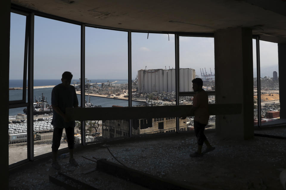 Workers remove debris from a destroyed building as they look at the site of the Aug. 4 explosion that hit the seaport of Beirut, Lebanon, Saturday, Aug. 15, 2020. (AP Photo/Bilal Hussein)