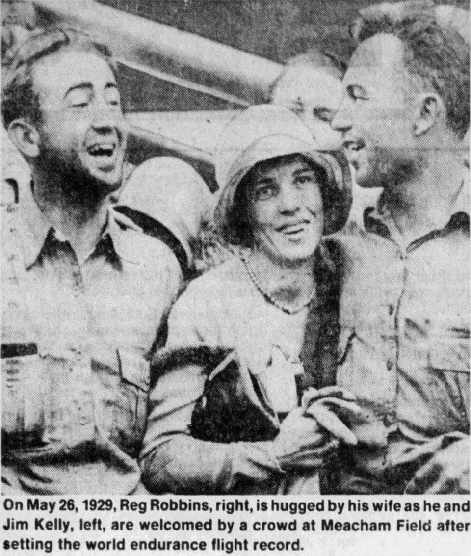 Reg L. Robbins, right, is hugged by his wife after he and James Kelly, left, completed their record-setting flight in 1929.