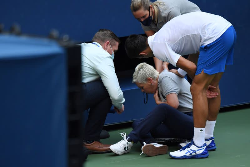 El tenista serbio Novak Djokovic y autoridades del torneo asisten a una jueza de línea que fue golpeada por una pelota de Djokovic