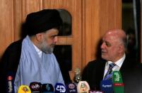 Iraqi Shi'ite cleric Moqtada al-Sadr, who's bloc came first, looks at Iraqi Prime Minister Haider al-Abadi, who's political bloc came third in a May parliamentary election, during a news conference in Najaf, Iraq June 23, 2018. REUTERS/Alaa al-Marjani