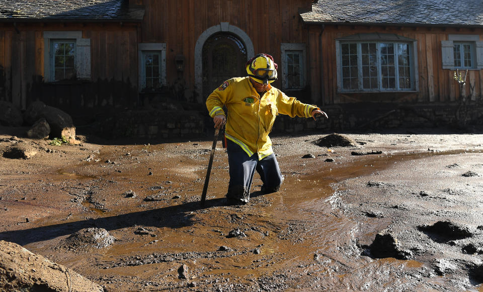 <p>Cal Firefighter Alex Jimenez walks out after finding a body under the mud at a house along Glen Oaks Drive in Montecito after a major storm hit the burn area Wednesday on Jan.10, 2018 in Montecito, California. (Photo: Wally Skalij/Los Angeles Times via Getty Images) </p>