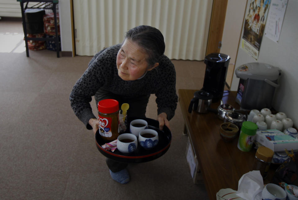 In this Monday, March 3, 2014 photo, Fusako Kudo, 73, a survivor of the March 11, 2011 tsunami, serves coffee at a temporary shelter in Tanohata, Iwate Prefecture, northeastern Japan. Kudo, a widow who survived being swept away by the tsunami, is resigned to a much longer wait. (AP Photo/Junji Kurokawa)