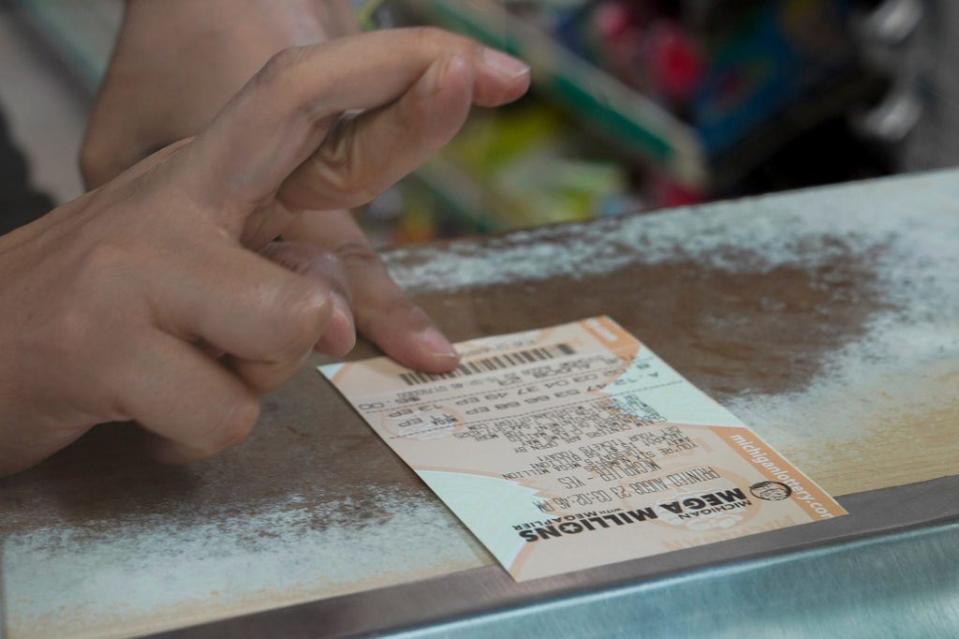 A woman crosses her fingers after buying a Mega Millions lottery ticket in Detroit on Tuesday, Aug. 8, 2023.