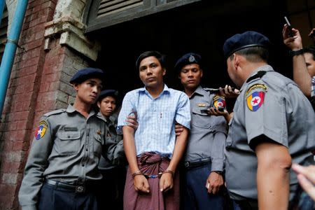 Detained Reuters journalist Kyaw Soe Oo is escorted by police while leaving after a court hearing in Yangon, Myanmar May 9, 2018. REUTERS/Stringer