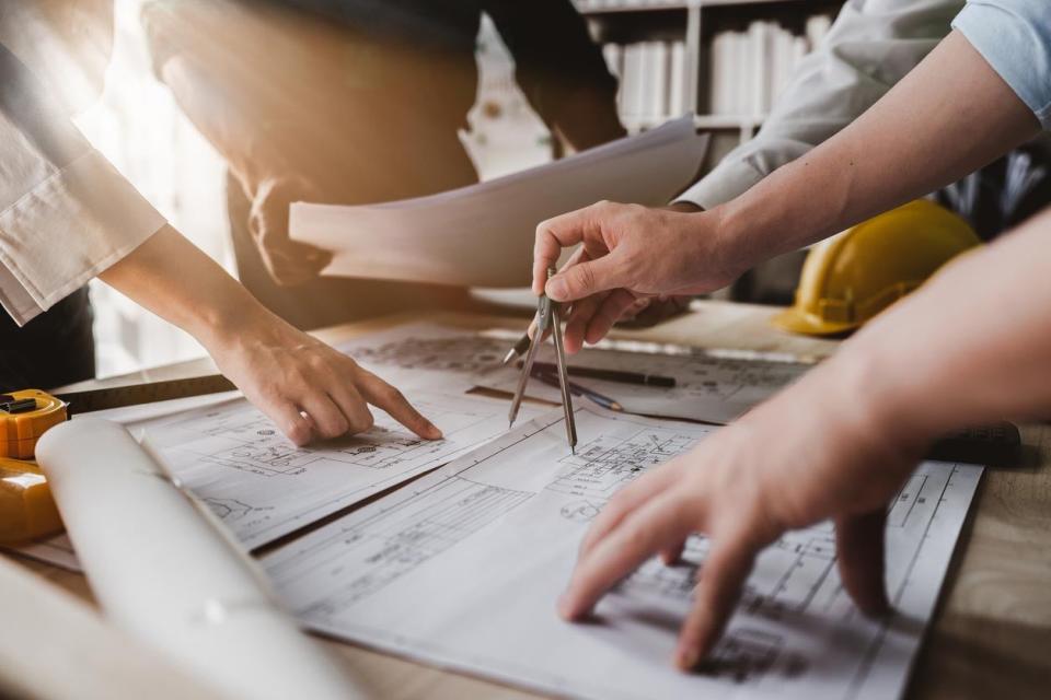 A group of people point to a discuss home building plans.