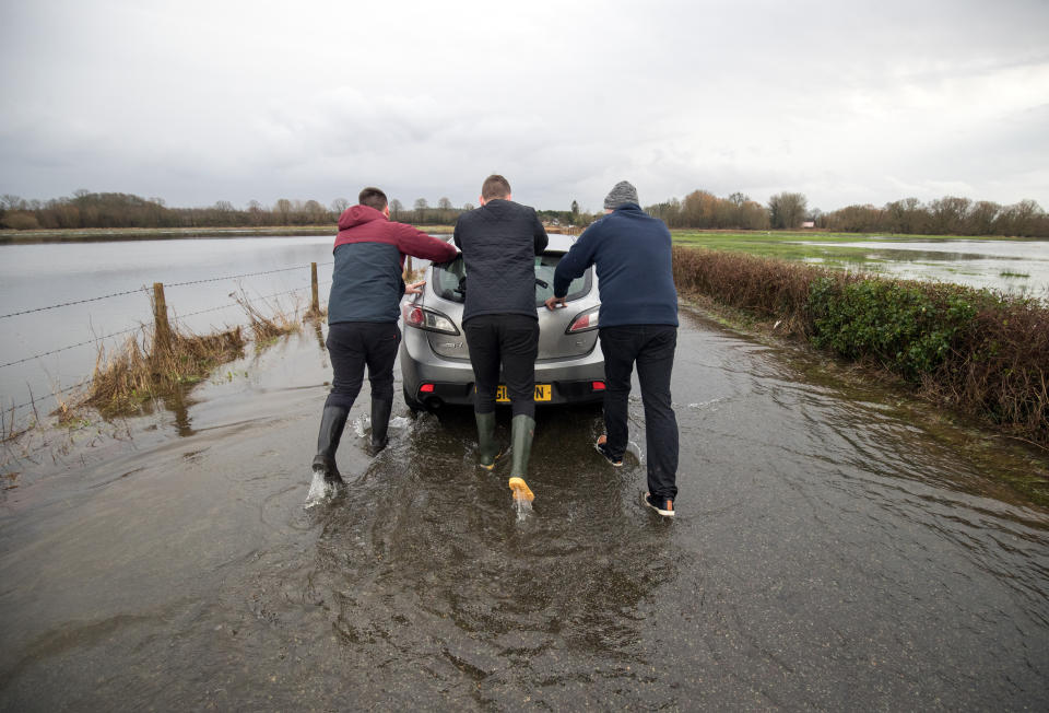 People push a car that was abandoned in floodwater near to Harbridge in Hampshire, in the aftermath of Storm Brendan.