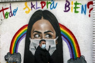 A man wearing a face mask walks past a graffiti reading in Spanish "Everything will be alright?" in Barcelona, Spain, Tuesday, Jan. 26, 2021. With nearly 2.5 million infections and 55,400 deaths for COVID-19 since the beginning of the pandemic, Spain ranks among the worst-hit countries by the coronavirus in Europe. (AP Photo/Emilio Morenatti)