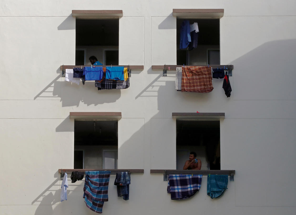 Migrant workers look out of windows in a dormitory, amid the coronavirus disease (COVID-19) outbreak in Singapore May 15, 2020.  REUTERS/Edgar Su