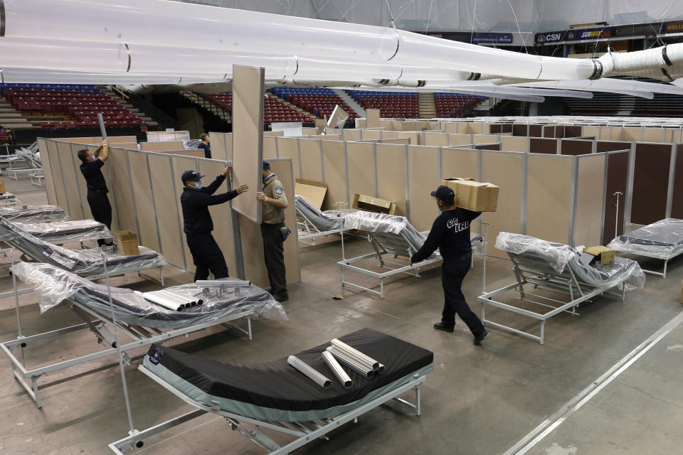 FILE - In this April 18, 2020, file photo, partitions are installed between beds as work is performed to turn Sleep Train Arena in Sacramento, Calif., into a 400-bed emergency field hospital to help deal with the coronavirus outbreak. Due to the recent spike in COVID-19 cases officials are rushing to reopen the former home of the NBA's Sacramento Kings, to patients. (AP Photo/Rich Pedroncelli, File)