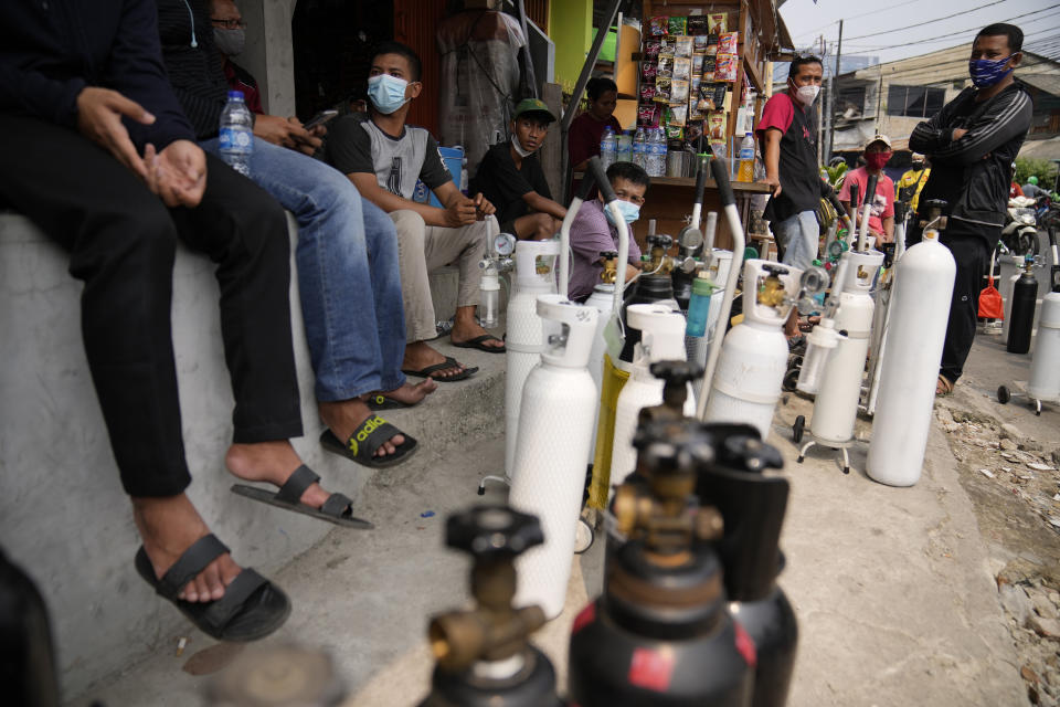 In this July 5, 2021, file photo, people queue up to refill their oxygen tanks at a filling station in Jakarta, Indonesia. Images of bodies burning in open-air pyres during the peak of the pandemic in India horrified the world in May, but in the last two weeks Indonesia and two other Southeast Asian nations have surpassed India’s peak per capita death rate as a new coronavirus wave tightens its grip on the region. (AP Photo/Dita Alangkara, File)