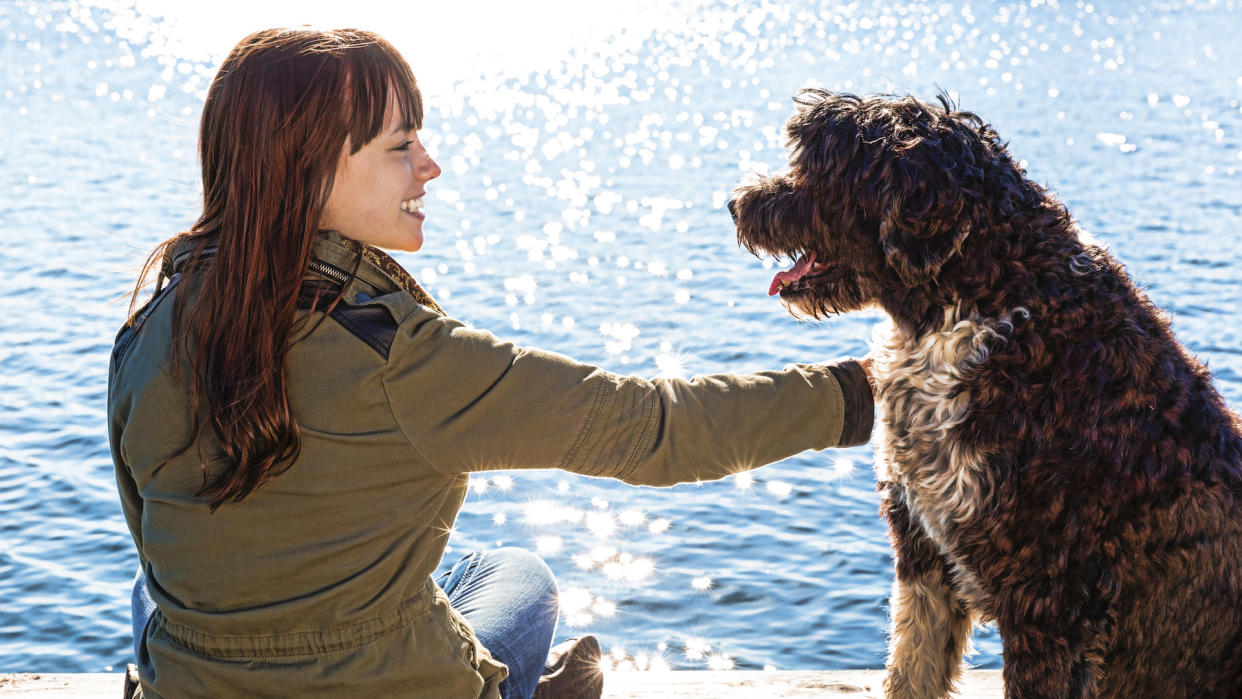 Lady smiling at her dog by waterside