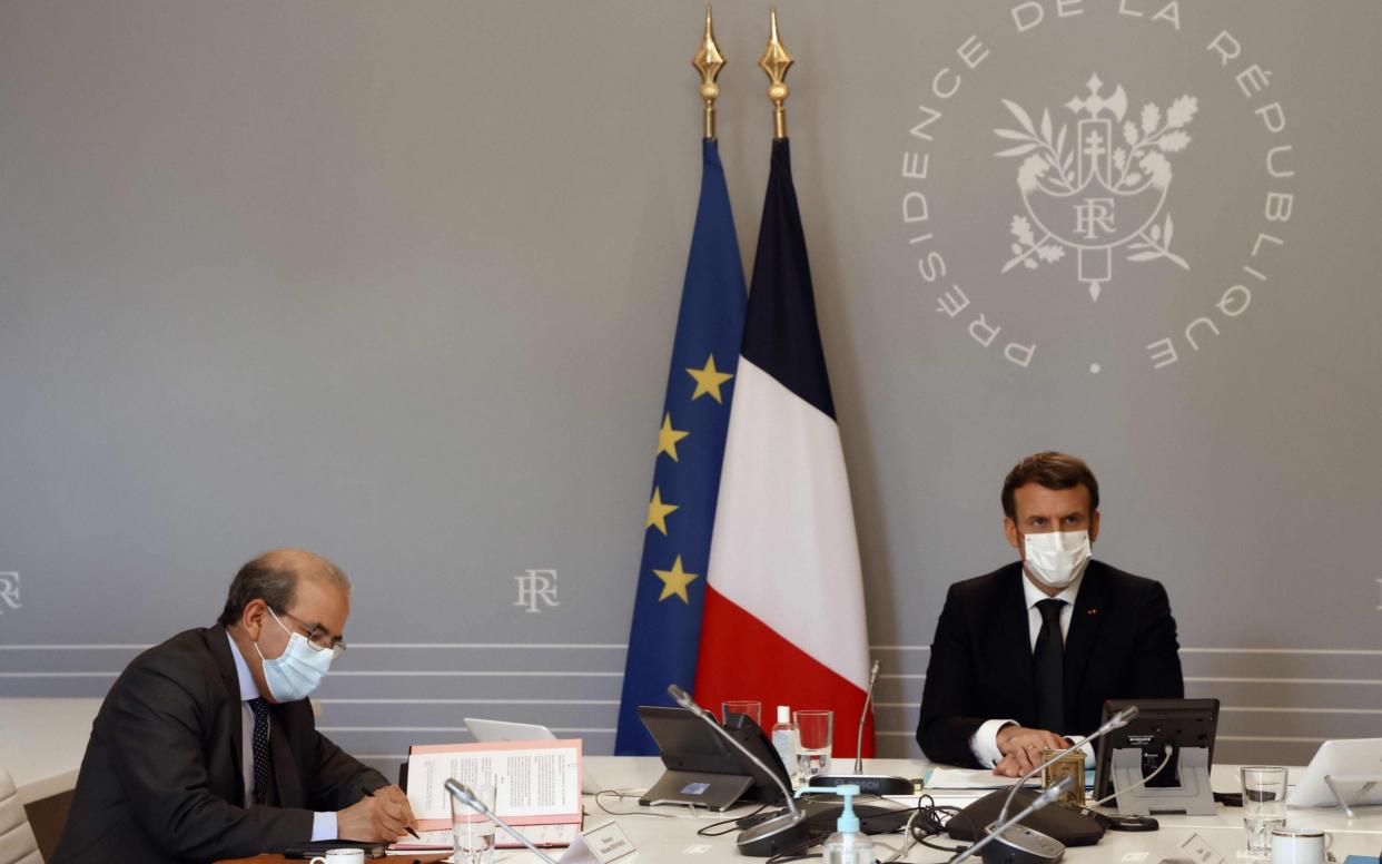 Mohammed Moussaoui, president of the French Council of the Muslim Faith, signs a "charter of principles" next to French President Emmanuel Macron - LUDOVIC MARIN/POOL/AFP via Getty Images