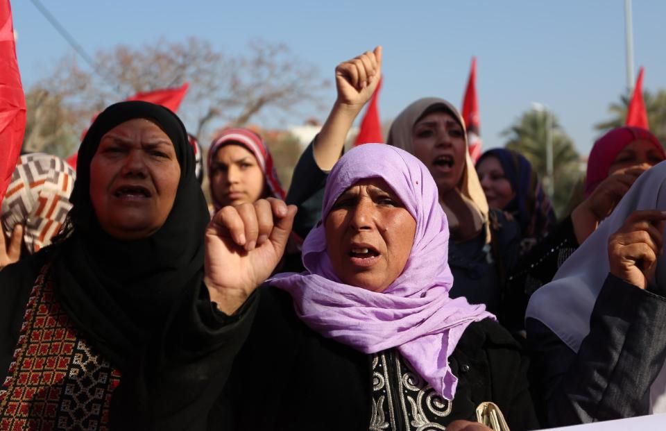 Palestinian women chant slogans and wave Palestinian and red flags, background, that represent the Palestinian Marxist-Leninist secular political and military organization, during a demonstration organized by the Democratic Front for the Liberation of Palestine, against resuming peace talks with Israel in Gaza City, Thursday, Jan. 2, 2014. As U.S. Secretary of State John Kerry returns to the region Thursday, the American message to the Israeli and Palestinian leaders is clear It's time to start making hard decisions , Kerry is bringing his own ideas for the outlines of a peace deal, and early indications are that the plan will include hard-to-swallow choices for both sides. (AP Photo/Hatem Moussa)