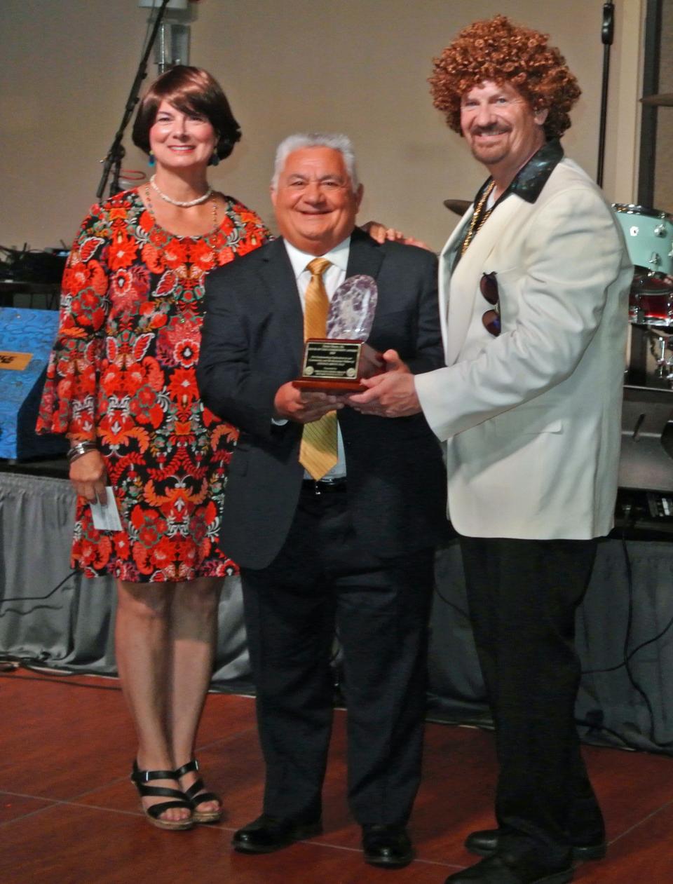 Ponte Vedra Beach Rotary Club president Lori Anderson and president elect Ron "Doc" Renuart (right) presented Ernie Bono with the Rock of the Community Award at the club's annual Mineral City Celebration, this year themed "Rotary Night Fever." Some guests, like Renuart, wore wigs and clothing that fit the '70s mode.