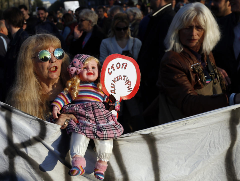 A woman holds a doll with a banner that reads: "Stop to dictatorship", during a protest march in Belgrade, Serbia, Sunday, April 9, 2017. Thousands of people have protested for the seventh consecutive day against the presidential election victory of Serbia's powerful Prime Minister Aleksandar Vucic, amid fresh allegations by the opposition of a rigged vote count. (AP Photo/Darko Vojinovic)