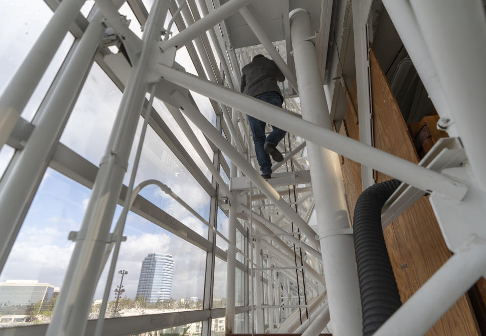 Kevin Cartwright, technician and president of Los Angeles-based Rosales Organ Builders, climbs to the top of the Hazel Wright organ at Christ Cathedral in Garden Grove, Calif., Tuesday, Feb. 15, 2022. The Hazel Wright organ, named after its original benefactor, now has 17,000 pipes, 15 divisions and 293 ranks. Ball said it is the largest pipe organ in a Roman Catholic cathedral in the Western Hemisphere. (AP Photo/Damian Dovarganes)