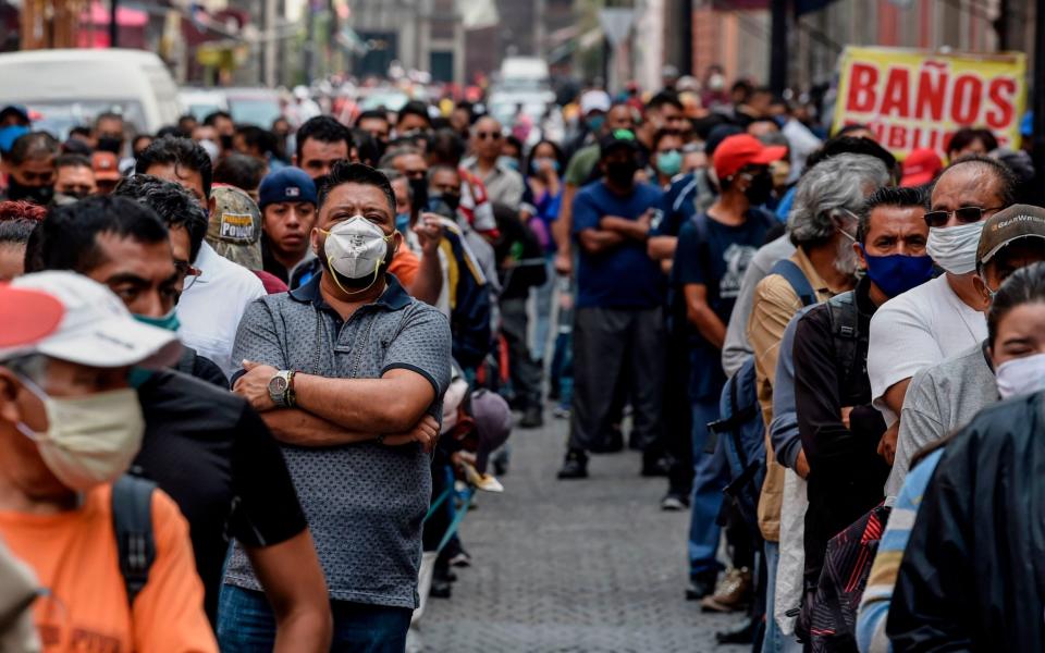 People queue in a street waiting to pass through a pedestrian control that limits the access in groups of 20 people to enter downtown Mexico City  - AFP