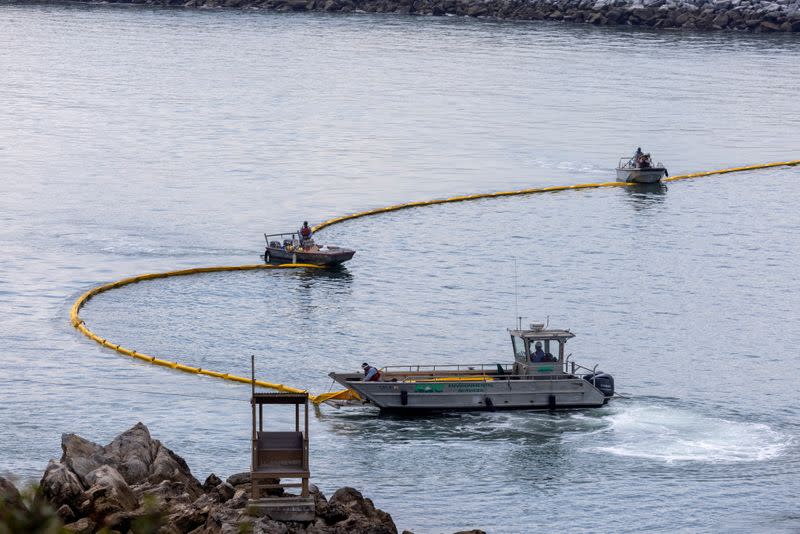 FILE PHOTO: Workers seal off Newport Beach harbor as a major California oil spill moves south down the coast