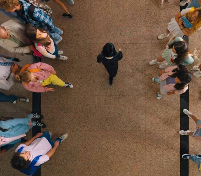 Girl in black walks down school hall in "Wednesday"