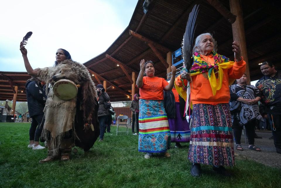 People dance during a ceremony to mark the one-year anniversary of the Tk'emlúps te Secwépemc announcement of the detection of the remains of 215 children at an unmarked burial site at the former Kamloops Indian Residential School, in Kamloops, B.C., on May 23, 2022. THE CANADIAN PRESS/Darryl Dyck