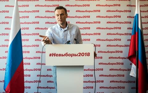 Alexei Navalny speaks on Sunday behind a podium reading "Non-election 2018" - Credit: Evgeny Feldman/Navalny Campaign via AP