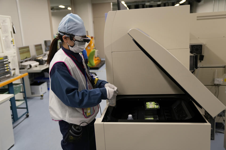 A lab technician wearing a pair of smart glasses demonstrates a part of a process to measure levels of tritium in water samples at one of the two laboratories at the Fukushima Daiichi nuclear power plant, run by Tokyo Electric Power Company Holdings (TEPCO), in Okuma town, northeastern Japan, Thursday, March 3, 2022. TEPCO and government officials say tritium, which is not harmful in small amounts, is inseparable from the water, but all other 63 radioactive isotopes selected for treatment can be reduced to safe levels, tested and further diluted by seawater before release. (AP Photo/Hiro Komae)