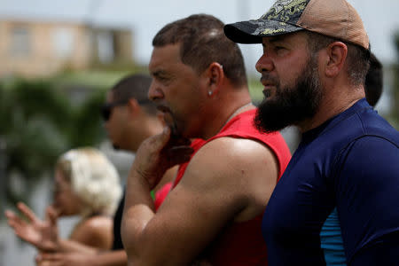 Local residents look at water flowing over the road at the dam of the Guajataca lake. REUTERS/Carlos Garcia Rawlins