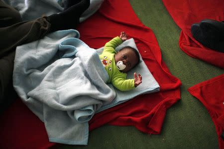 An African child immigrant lies inside a sports center after arriving on a rescue ship at the southern Spanish port of Tarifa, near Cadiz, southern Spain August 12, 2014. REUTERS/Jon Nazca