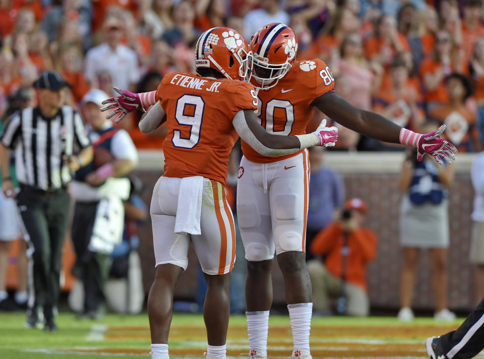 Travis Etienne celebrates with Milan Richard. Etienne scored 3 TDs against NC State. (AP)