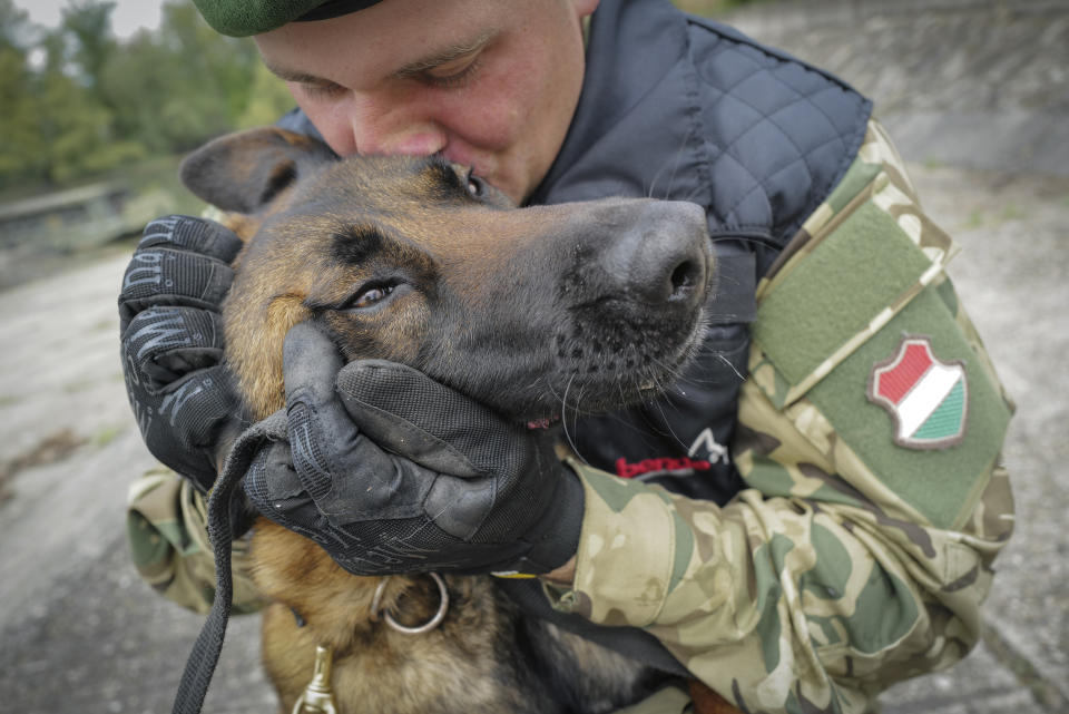 Sgt. 1st Class Balazs Nemeth and his bomb sniffer dog Logan are seen together at the garrison of Explosive Ordnance Disposal and Warship Regiment of the Hungarian Defense Forces in Budapest, Hungary, April 28, 2022. Logan, a two-year-old Belgian shepherd, has received a second chance after being rescued from abusive owners and recruited to serve in an elite military bomb squad. Logan is undergoing intensive training as an explosive detection dog for the Hungarian Defense Forces. (AP Photo/Bela Szandelszky)
