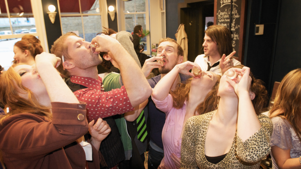 A group of people drink shots at an office Christmas party.