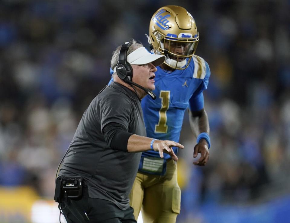 UCLA coach Chip Kelly stands next to quarterback Dorian Thompson-Robinson.